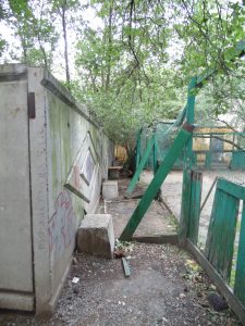 Бетонный забор почти вплотную граничит с разваливающейся хоккейной коробкой